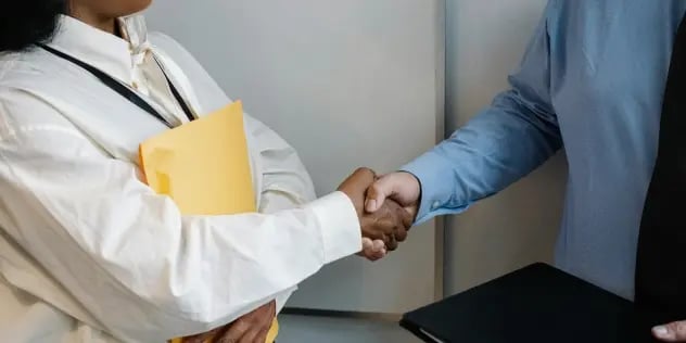 A man and a woman shaking hands in a professional setting.