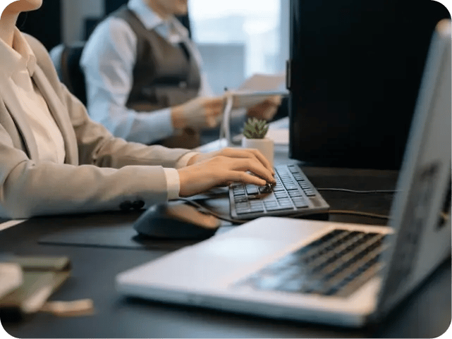 A close-up of hands typing on a laptop keyboard in a professional office setting.