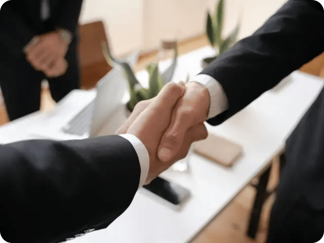 A close-up of two corporate men shaking hands, focusing on the professional handshake.