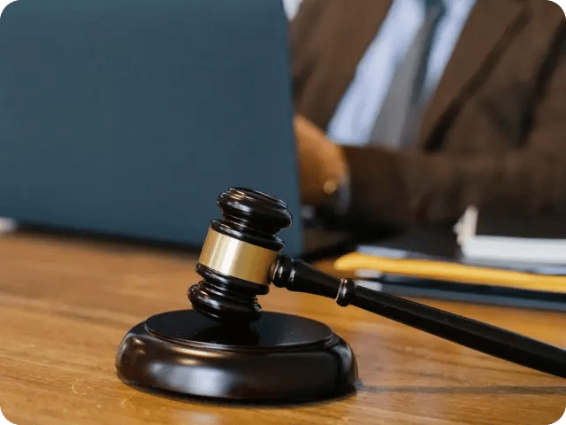 A man in a professional setting with a judicial gavel positioned in the foreground.