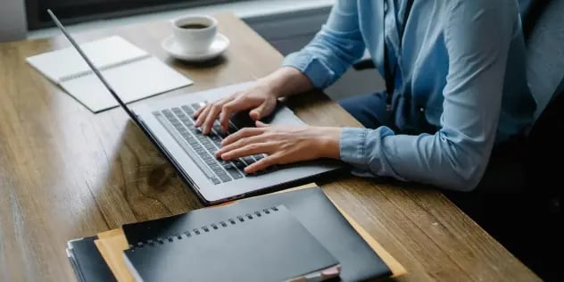 A person working at a desk on a laptop, surrounded by organized files.